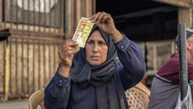 صورة بالغراء والصبر… فلسطينية تُعيد الحياة للأوراق النقدية الممزقة في أسواق غزة المحاصرة