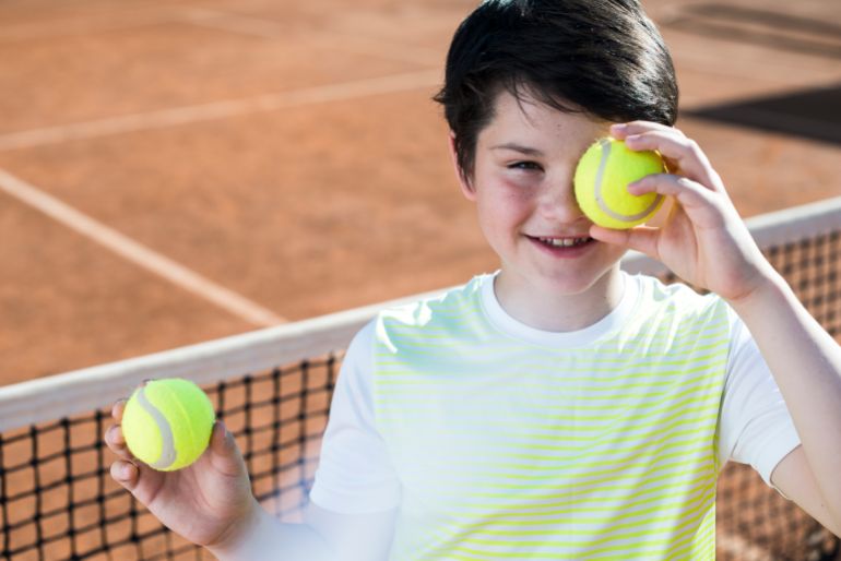 Kid covering his eye with a tennis ball freepik